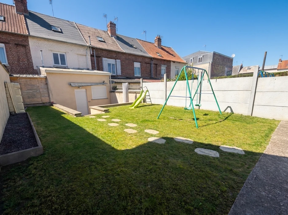 Jardin privatif clôturé en milieu urbain, avec pelouse tondue, pas japonais en dalles de pierre naturelle, bac de plantation en bois traité