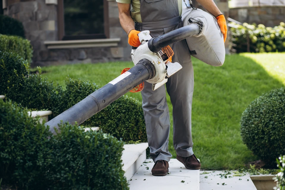 Homme en tenue de travail utilisant un nettoyeur haute pression sur une terrasse extérieure
