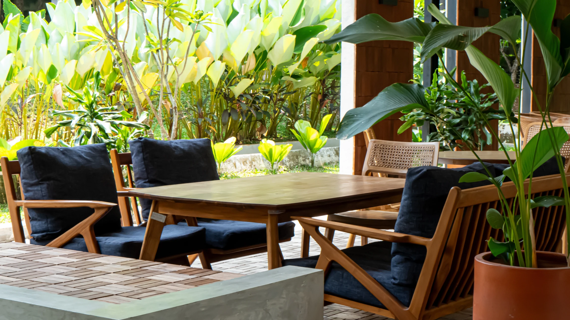Terrasse en bois composite aménagée avec plusieurs pots de fleurs colorées disposés stratégiquement, incluant des géraniums, pétunias et autres fleurs estivales vibrantes, avec mobilier de terrasse discret en arrière-plan, photographiée de jour sous un éclairage naturel.